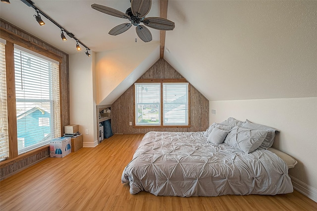 bedroom featuring lofted ceiling, rail lighting, ceiling fan, and light wood-type flooring