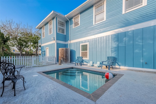 back of property with a fenced in pool and a patio