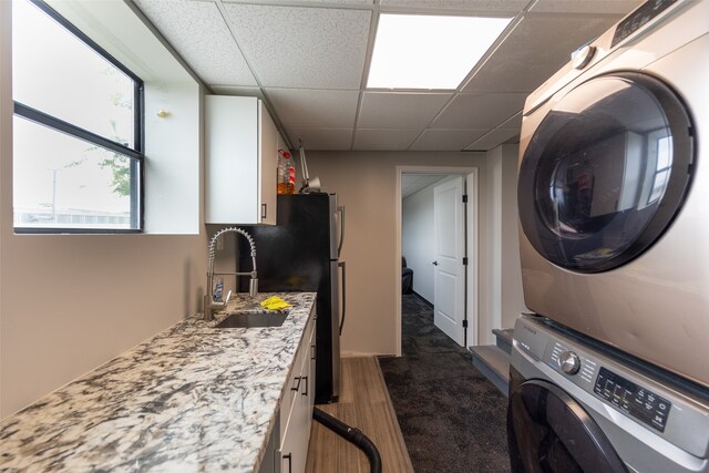 clothes washing area with stacked washer / dryer, sink, and dark carpet