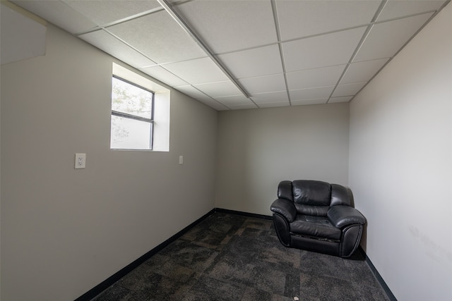 sitting room featuring dark carpet and a paneled ceiling