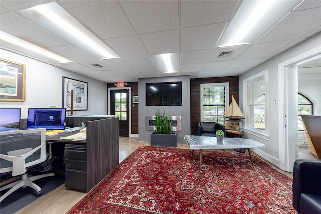 office space featuring a drop ceiling, a fireplace, and a wealth of natural light