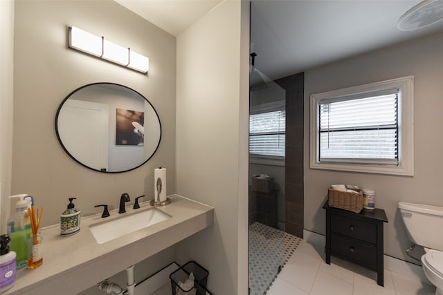 bathroom featuring a tile shower, toilet, sink, and tile patterned flooring