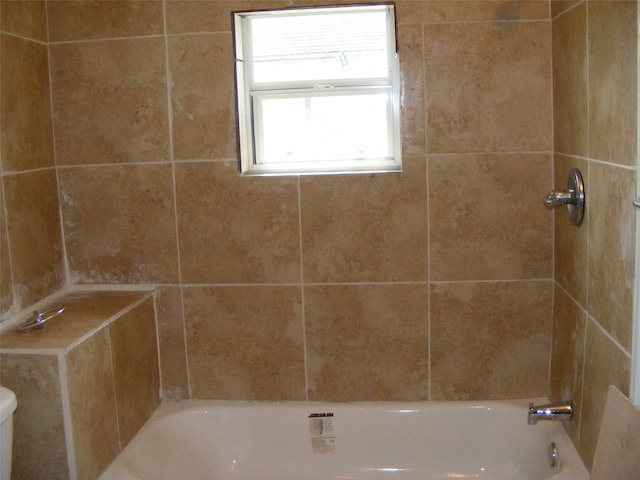 bathroom featuring tiled shower / bath combo and toilet