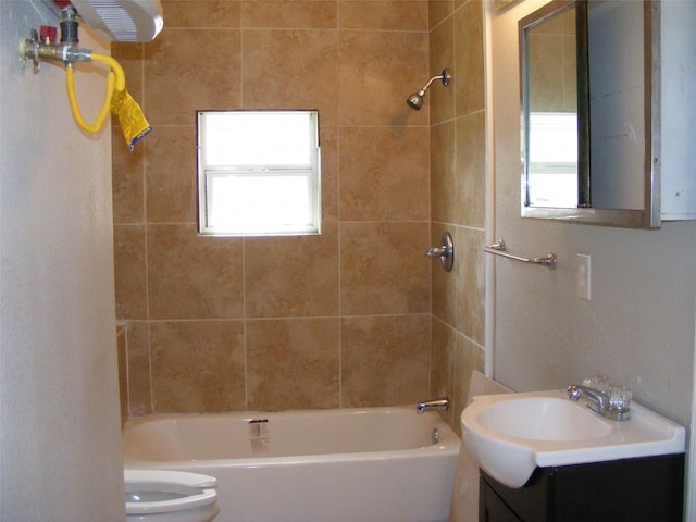 full bathroom with vanity, tiled shower / bath, toilet, and plenty of natural light