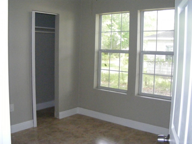 unfurnished bedroom with multiple windows, a closet, and dark tile patterned flooring