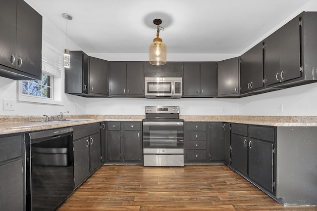 kitchen featuring appliances with stainless steel finishes, dark hardwood / wood-style flooring, sink, and pendant lighting