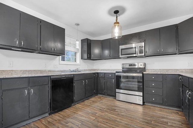 kitchen featuring dark hardwood / wood-style flooring, decorative light fixtures, sink, and stainless steel appliances