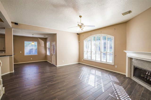 unfurnished living room with dark wood-type flooring, a textured ceiling, and ceiling fan