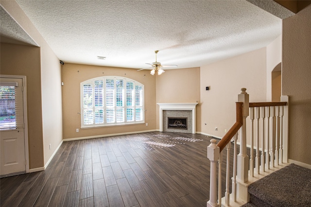 unfurnished living room with a textured ceiling, dark wood-type flooring, and ceiling fan