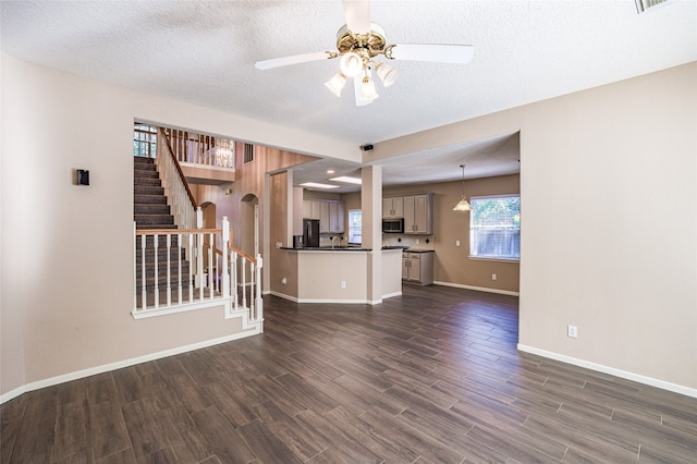 unfurnished living room featuring a textured ceiling, dark wood-type flooring, and ceiling fan