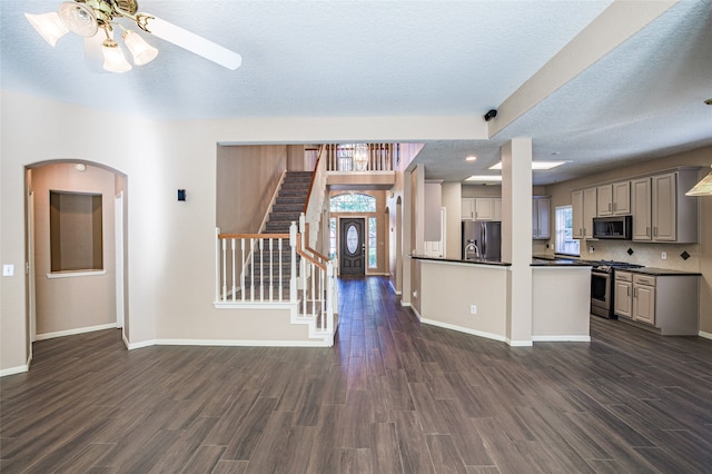 kitchen with a textured ceiling, ceiling fan, stainless steel appliances, and dark hardwood / wood-style flooring