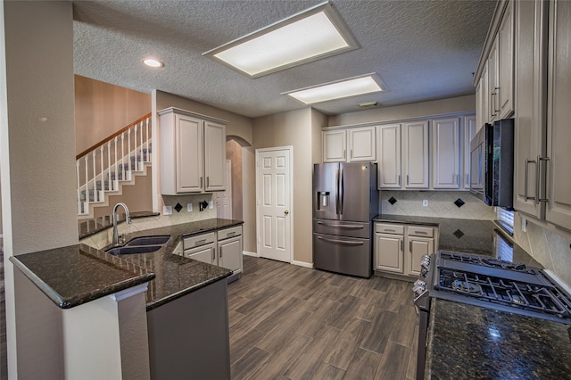 kitchen featuring kitchen peninsula, tasteful backsplash, dark hardwood / wood-style flooring, black appliances, and sink