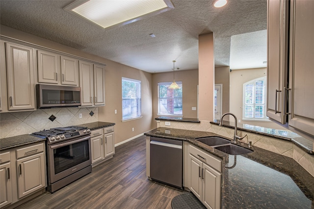 kitchen featuring sink, appliances with stainless steel finishes, dark hardwood / wood-style floors, and dark stone counters