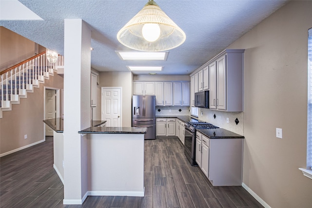 kitchen featuring tasteful backsplash, appliances with stainless steel finishes, decorative light fixtures, and dark hardwood / wood-style floors