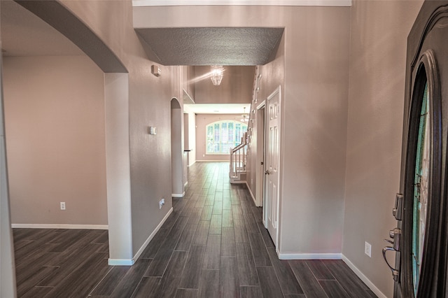 hallway with a textured ceiling and dark wood-type flooring