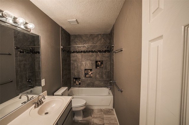 full bathroom featuring vanity, toilet, a textured ceiling, and tiled shower / bath