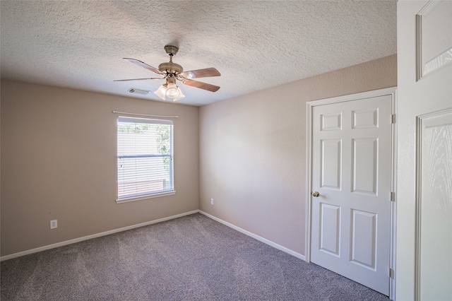 carpeted empty room featuring ceiling fan and a textured ceiling