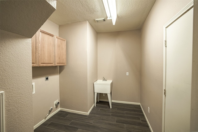 laundry area featuring cabinets, dark hardwood / wood-style floors, a textured ceiling, and electric dryer hookup