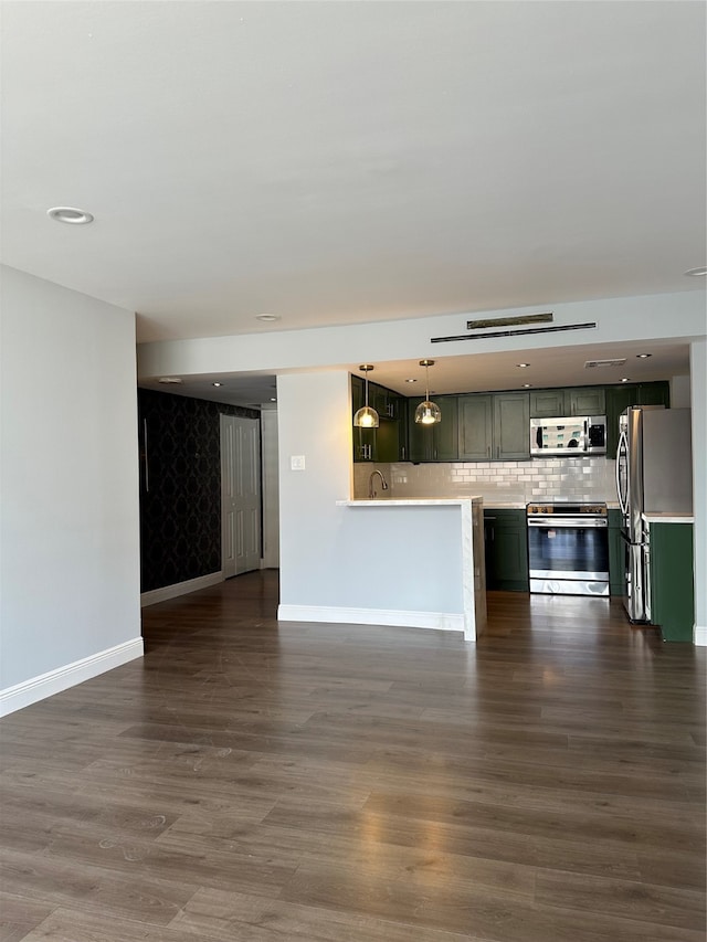 kitchen featuring decorative backsplash, dark hardwood / wood-style floors, sink, pendant lighting, and stainless steel appliances