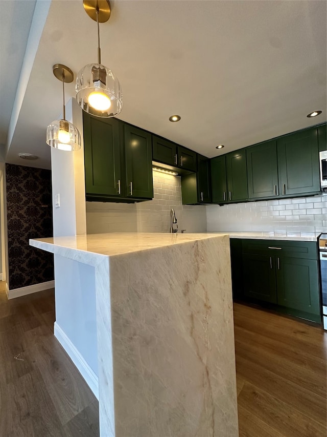 kitchen featuring decorative light fixtures, kitchen peninsula, green cabinets, and dark hardwood / wood-style flooring