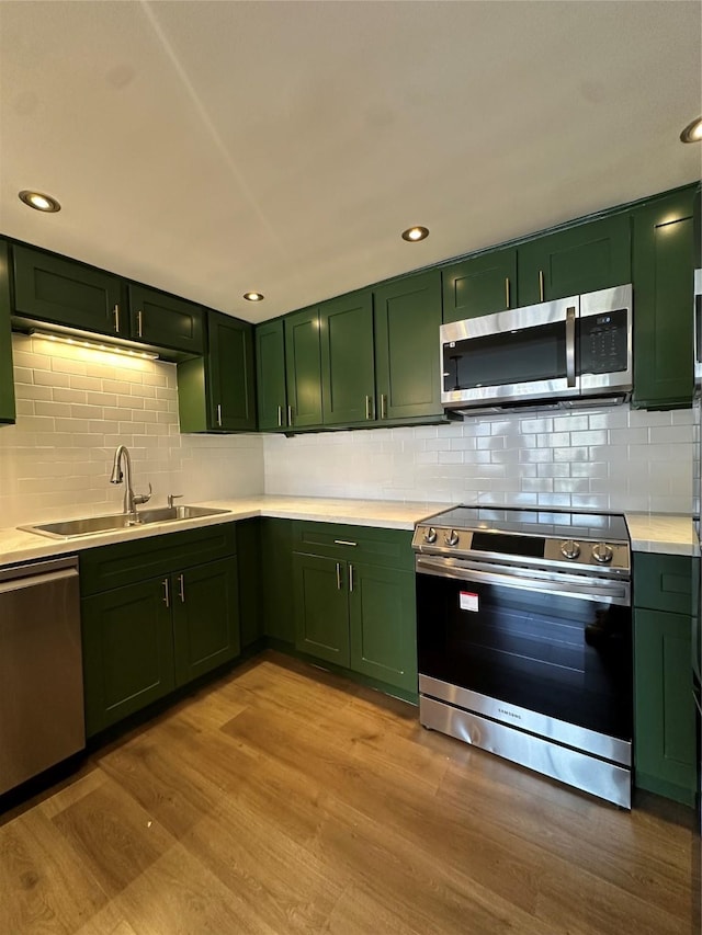 kitchen with green cabinets, appliances with stainless steel finishes, a sink, and recessed lighting