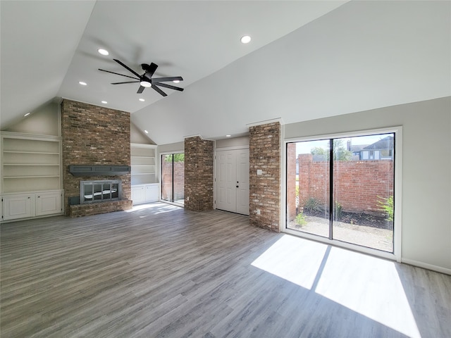 unfurnished living room featuring a fireplace, ceiling fan, vaulted ceiling, hardwood / wood-style flooring, and built in shelves