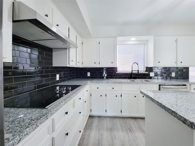 kitchen with black electric stovetop, decorative backsplash, sink, light wood-type flooring, and white cabinets