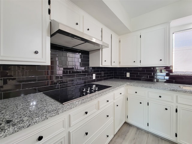 kitchen with black electric stovetop, light stone counters, white cabinetry, and light hardwood / wood-style flooring