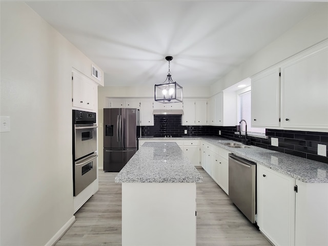 kitchen featuring sink, a center island, white cabinetry, stainless steel appliances, and pendant lighting