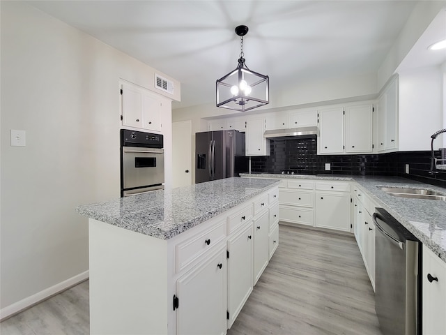 kitchen featuring stainless steel appliances, sink, a center island, pendant lighting, and white cabinetry