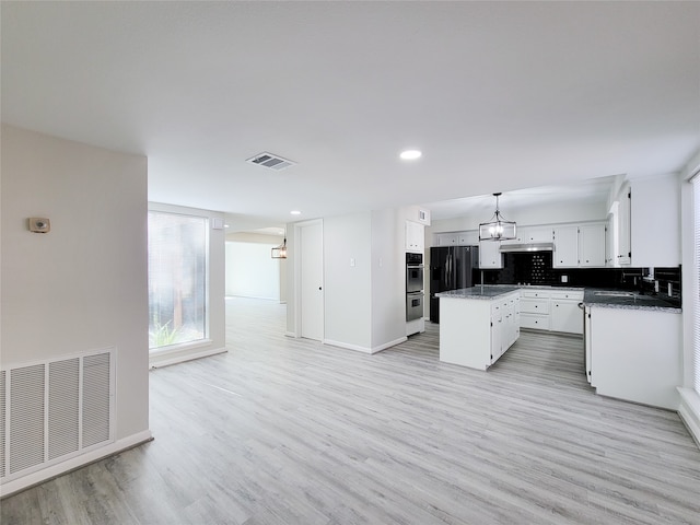 kitchen featuring decorative backsplash, a kitchen island, light hardwood / wood-style flooring, black refrigerator, and pendant lighting