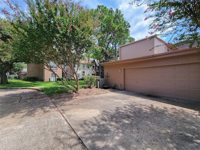 exterior space with a yard, a garage, and central AC unit