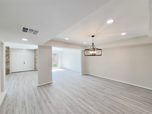 empty room with a notable chandelier and light hardwood / wood-style floors