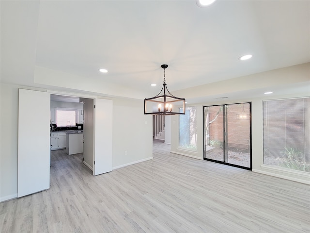 unfurnished room with sink, light hardwood / wood-style flooring, and an inviting chandelier