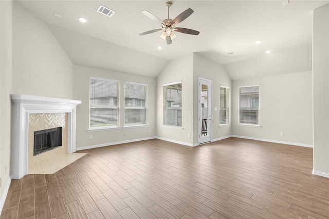 unfurnished living room featuring hardwood / wood-style floors, vaulted ceiling, a tiled fireplace, and ceiling fan