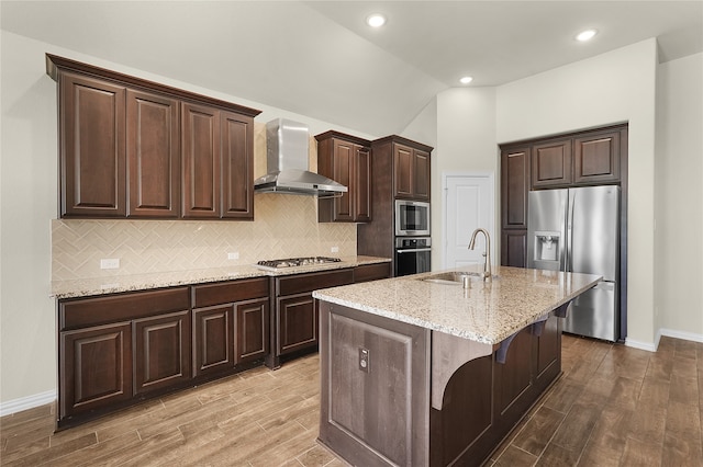 kitchen featuring appliances with stainless steel finishes, wall chimney exhaust hood, sink, and light hardwood / wood-style flooring