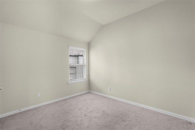 carpeted empty room with vaulted ceiling