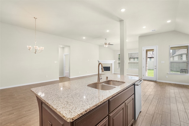 kitchen featuring sink, hanging light fixtures, light hardwood / wood-style floors, lofted ceiling, and a center island with sink