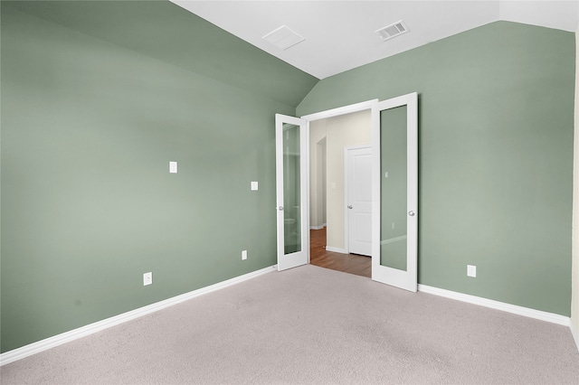 unfurnished bedroom with french doors, vaulted ceiling, and carpet flooring