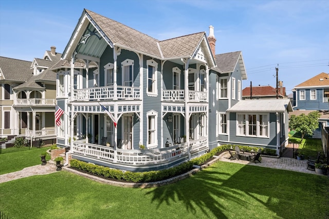 rear view of property with covered porch, a lawn, and a balcony