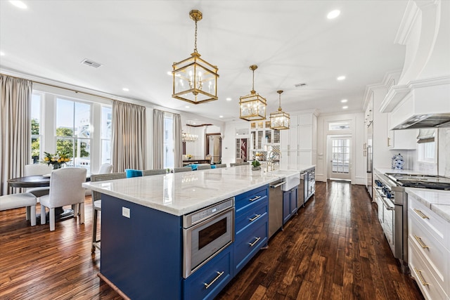 kitchen featuring high quality appliances, a large island, decorative light fixtures, blue cabinets, and white cabinetry