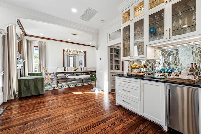 kitchen with tasteful backsplash, white cabinetry, decorative light fixtures, ornamental molding, and dark hardwood / wood-style floors