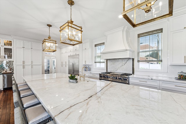 kitchen with high quality appliances, hanging light fixtures, dark wood-type flooring, and plenty of natural light