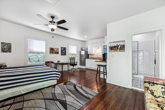 bedroom featuring ensuite bathroom, sink, ceiling fan, dark wood-type flooring, and stainless steel refrigerator