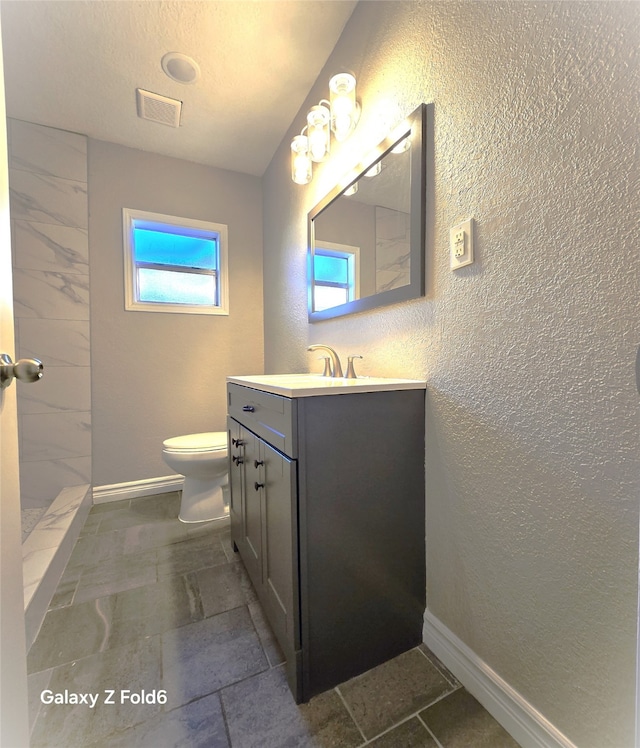 bathroom featuring vanity, toilet, and walk in shower