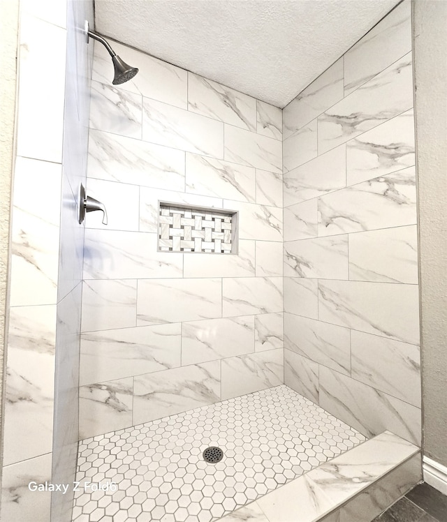 bathroom with tiled shower and a textured ceiling