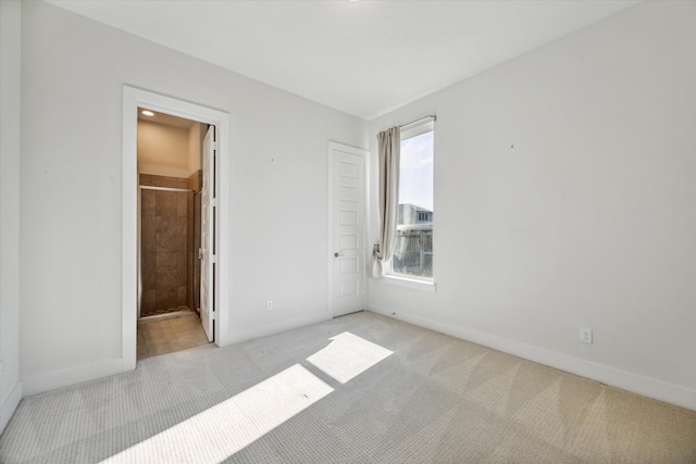 unfurnished bedroom featuring ensuite bathroom and light colored carpet