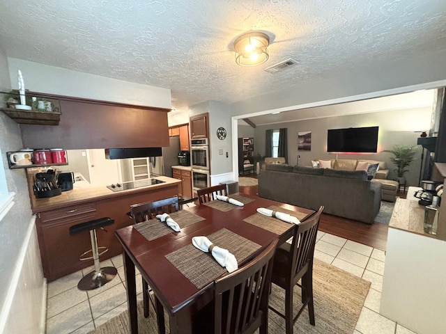 dining space featuring a textured ceiling and light hardwood / wood-style floors