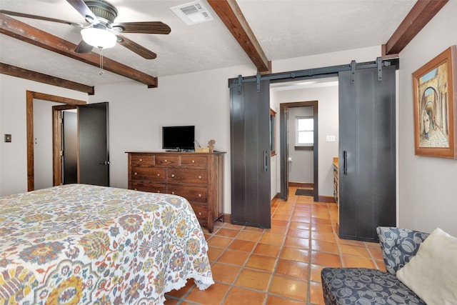 bedroom featuring ceiling fan, a textured ceiling, a barn door, beamed ceiling, and tile patterned floors