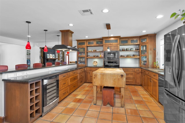 kitchen featuring wooden counters, hanging light fixtures, kitchen peninsula, black appliances, and beverage cooler